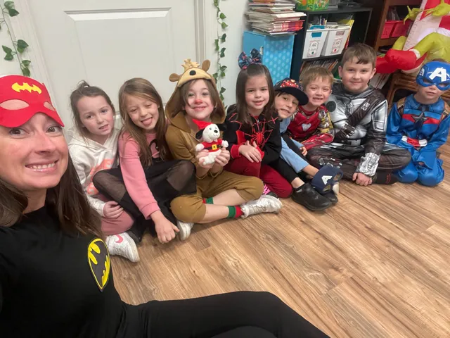 A teacher and students in superhero costumes sitting together on dress-up day