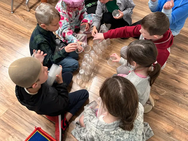 Young students working together on a cup-stacking activity on the classroom floor