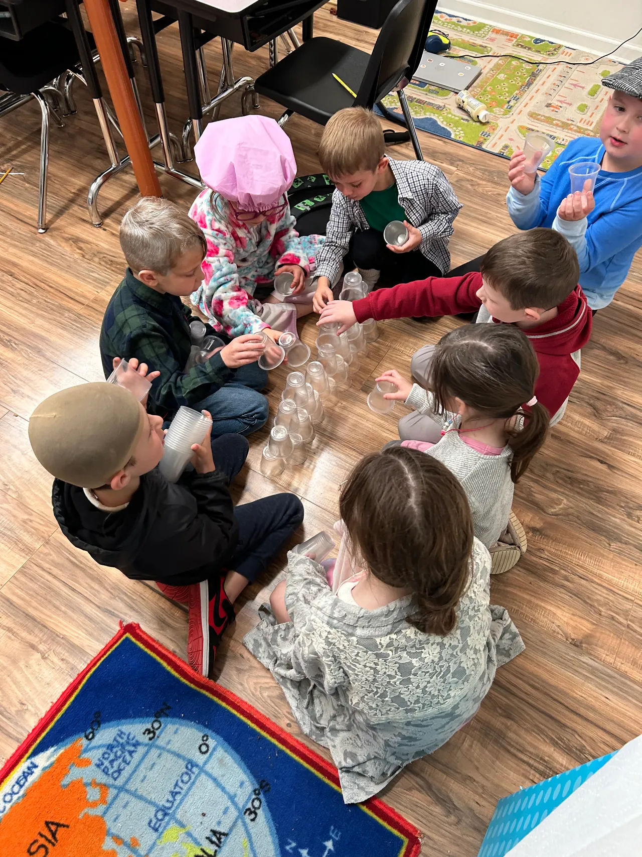 Young students working together on a cup-stacking activity on the classroom floor
