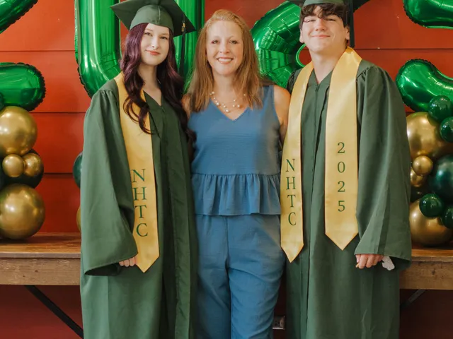 Two graduates in gold NHTC stoles celebrating with their teacher