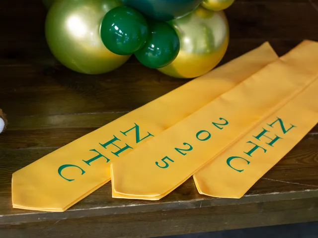 Gold NHTC graduation stoles laid out beside green and gold balloons