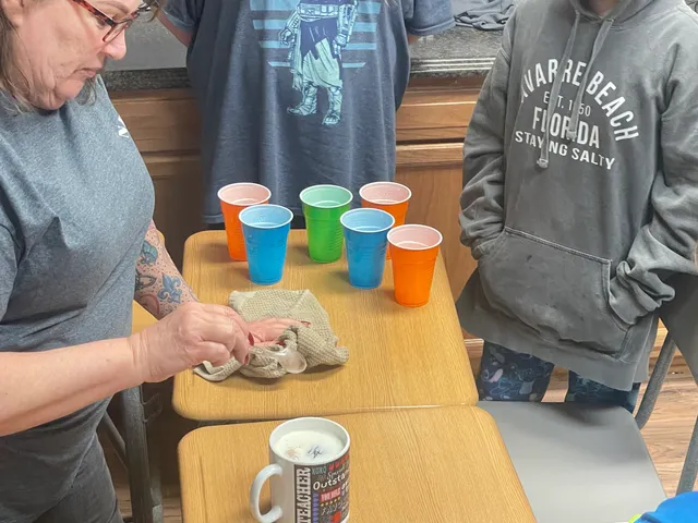 A teacher leading a colorful cup science demonstration for students